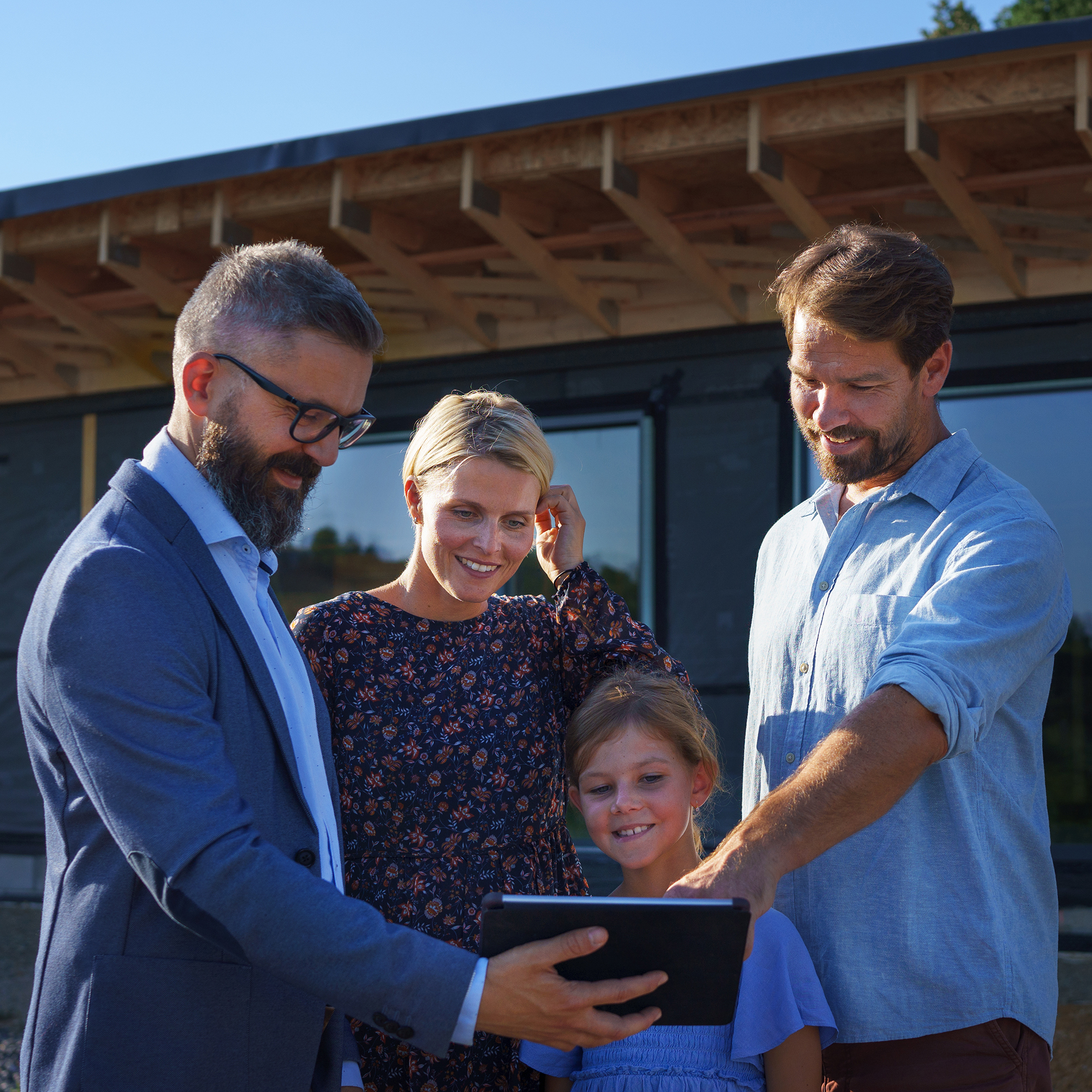 Sales Agent showing plans of new house to young family on construction site.