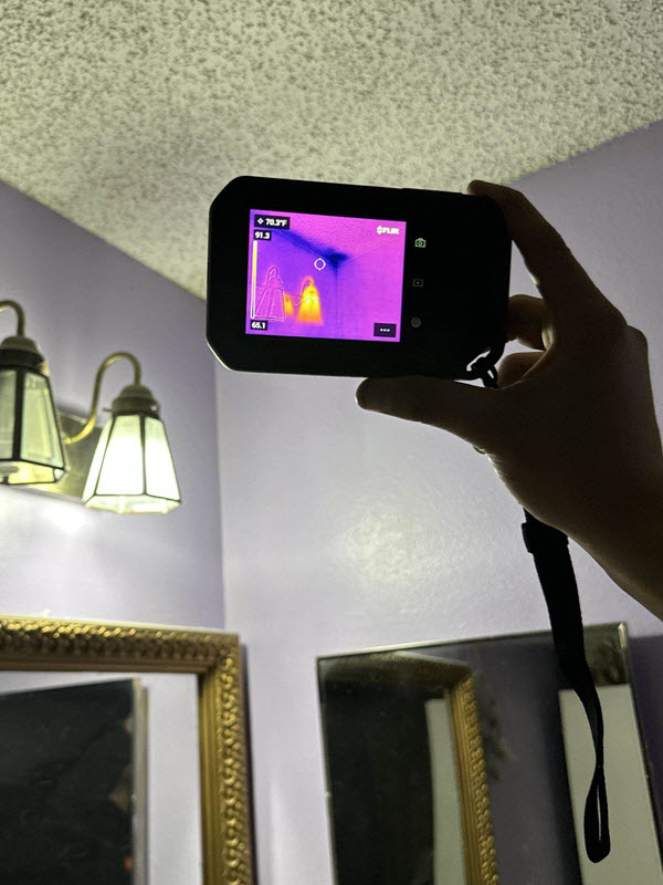 Abbotts' technician is using infrared thermal imaging to detect hidden water damage behind a wall during an Aurora, CO home inspection